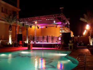 Beautiful lighted stage by a hotel swimming pool, ready for a concert