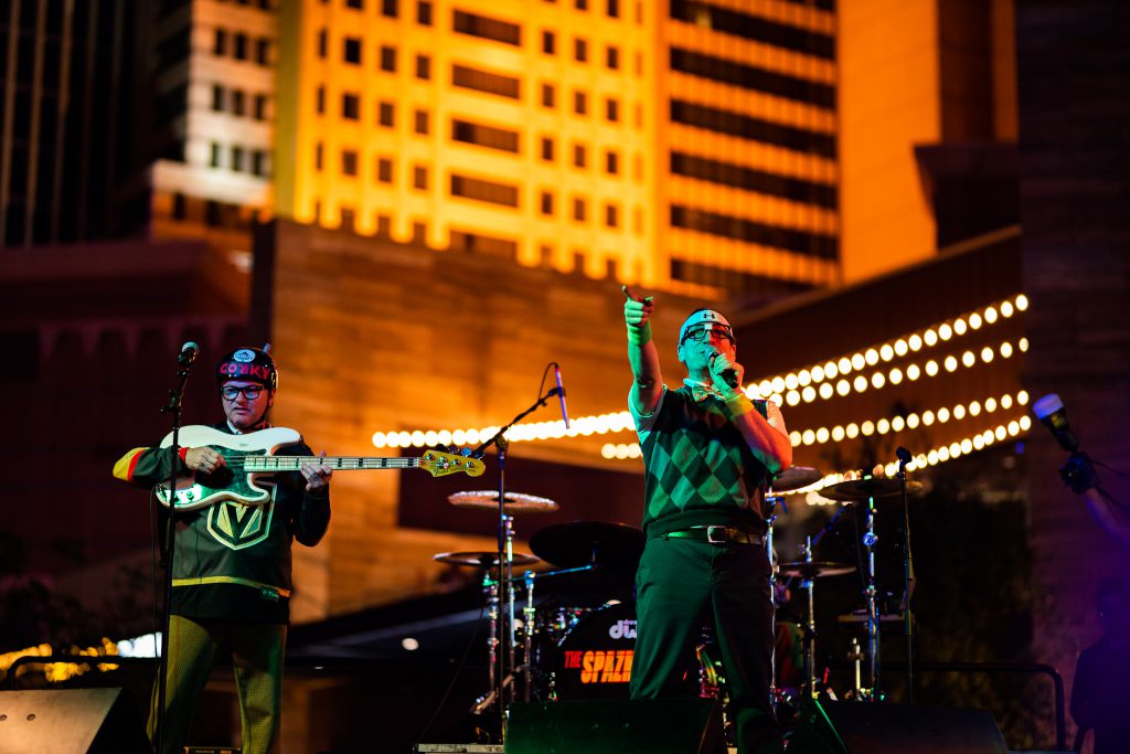 band on stage playing guitar wearing golden knights swag