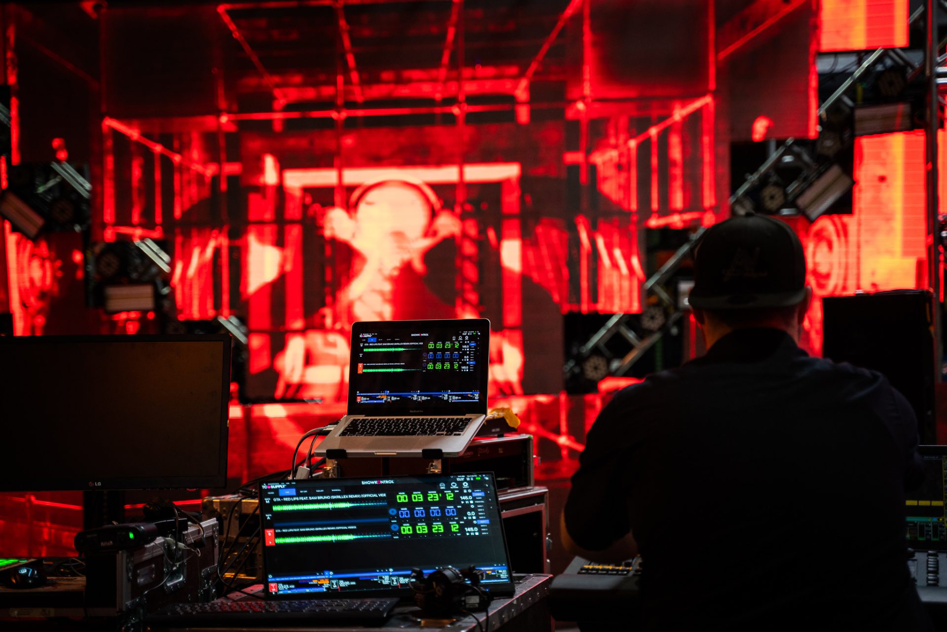 two team-members work side by side programming a video wall and lighting structure for a rave
